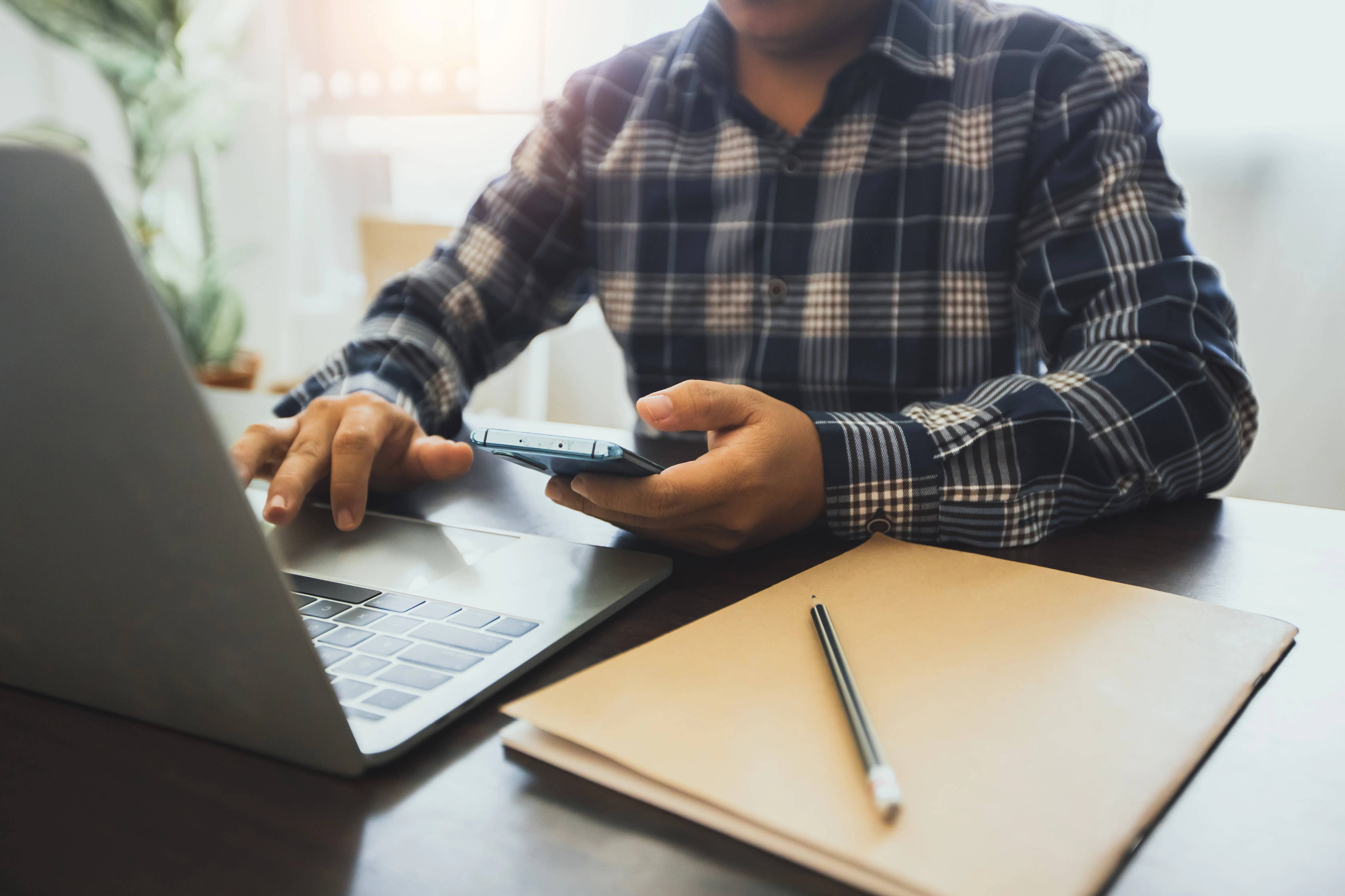 Homme qui vérifie les informations entre son ordinateur et son téléphone portable