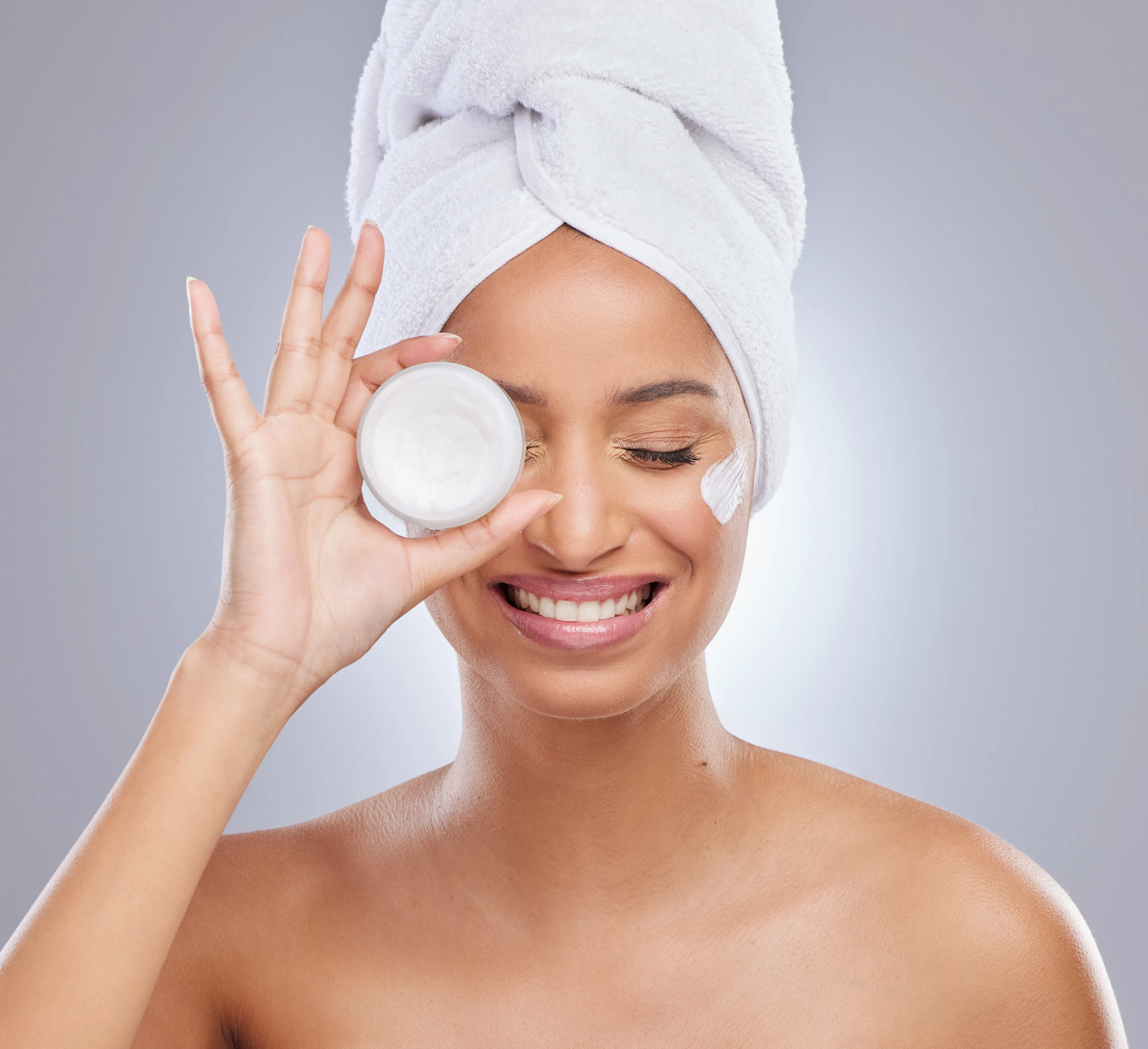 Femme souriante tenant une crème hydratante
