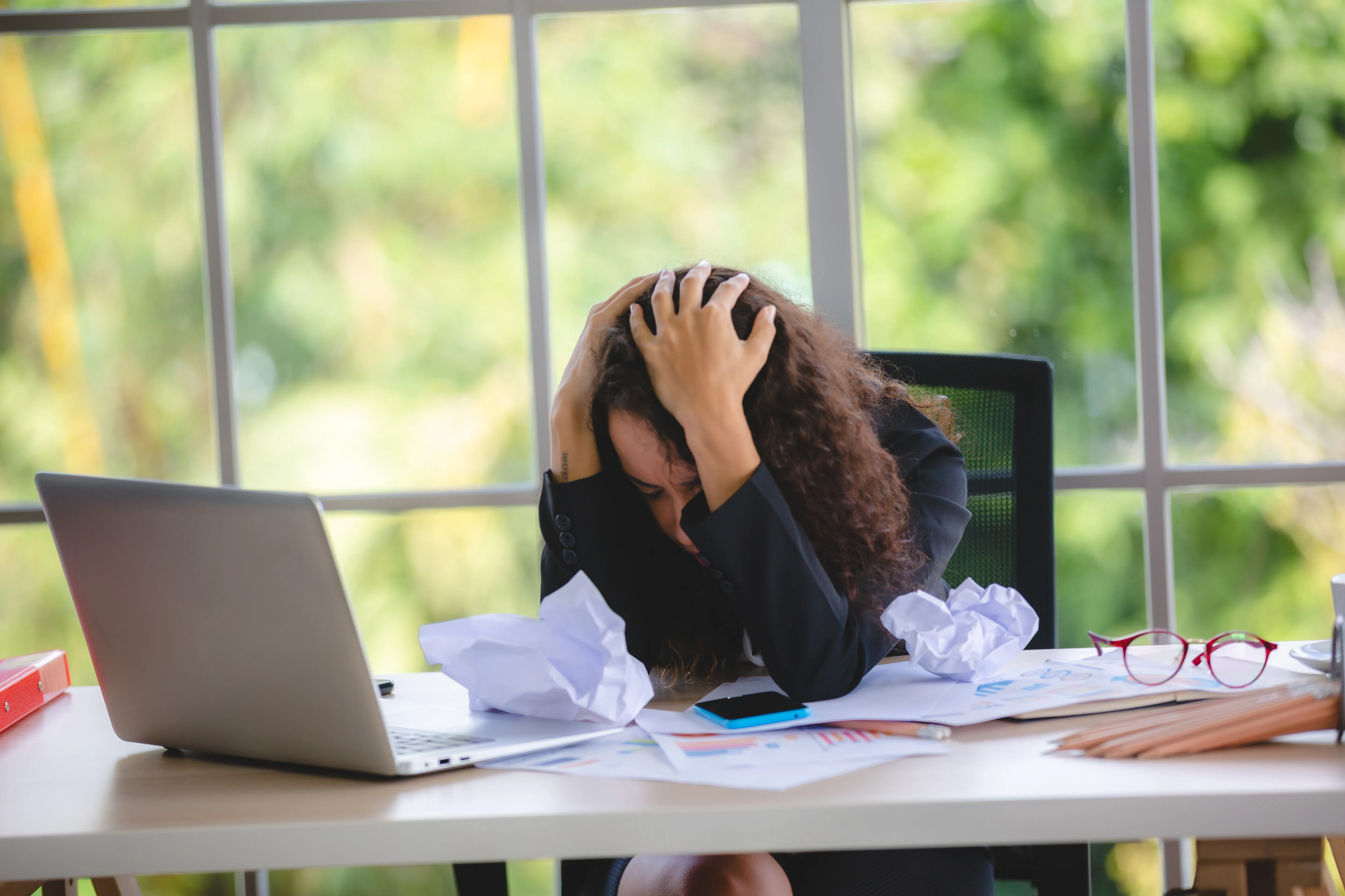 Femme se tenant la tête avec l'air épuisé devant un ordinateur